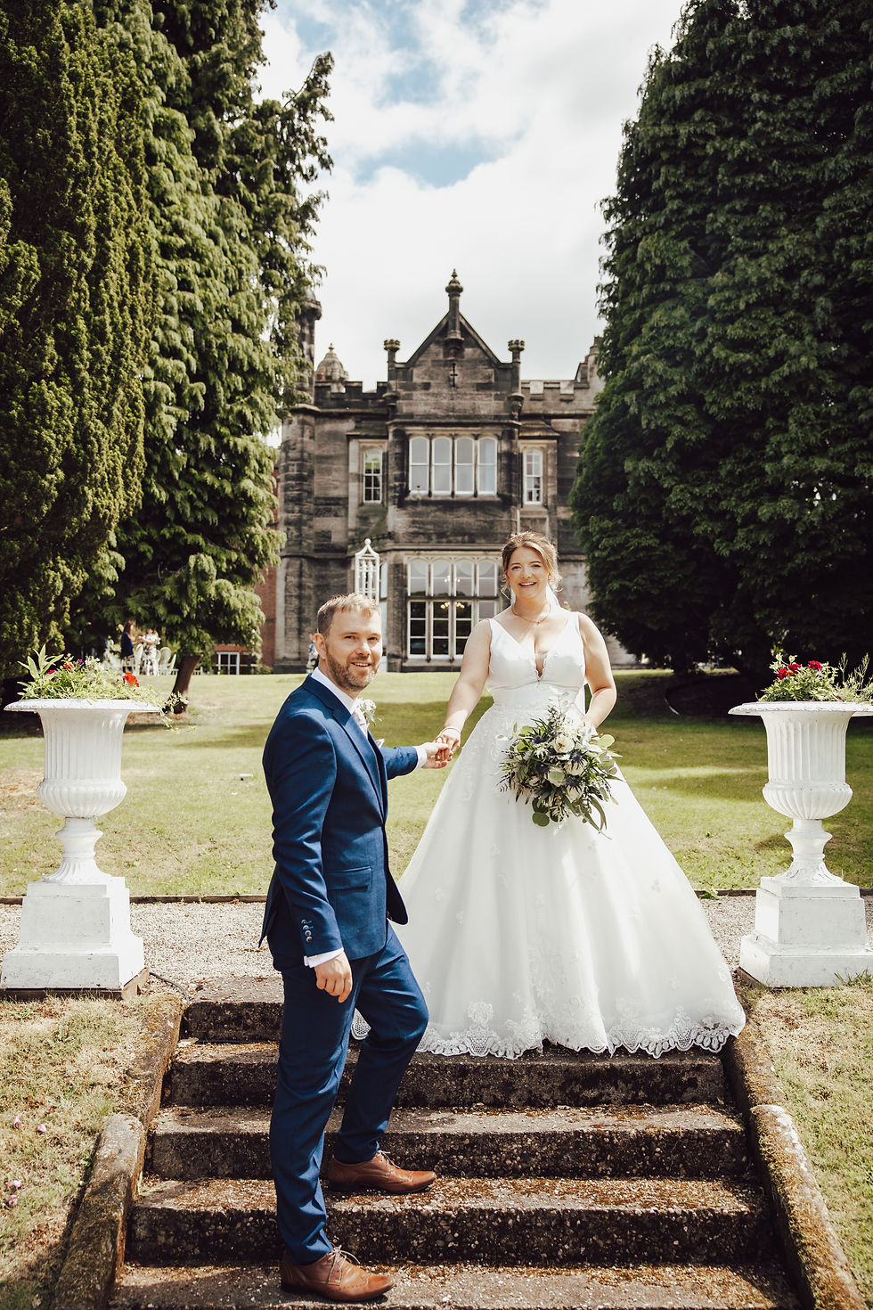 Wedding couple holding hands and walking through the gardens of Hawkesyard Estate, UK
