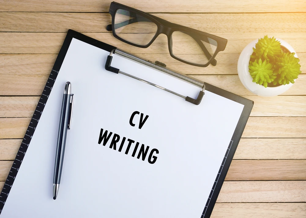 A professionally written resume with a successful job interview in the background, representing the benefits of hiring a CV writer.