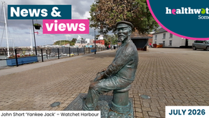 Photograph of a bronze statue of John Short depicting a seated fisherman wearing a cap, positioned on a cobblestone promenade near a marina with boats and buildings in the background. The statue is detailed with textured clothing and sits on a bollard, symbolising maritime heritage in the coastal town setting of Watchet, Somerset. News & views, Healthwatch Somerset, and July 2026 text.