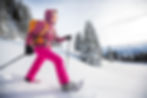 Pretty, young woman snowshoeing in high mountains, enjoying splendid winter weather with a