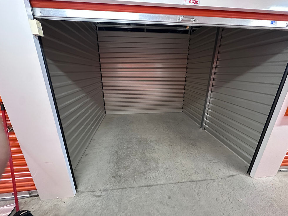 Photo of an empty storage unit with open door, gray metal walls and concrete floor, landscape aspect ratio, clean and spacious interior.