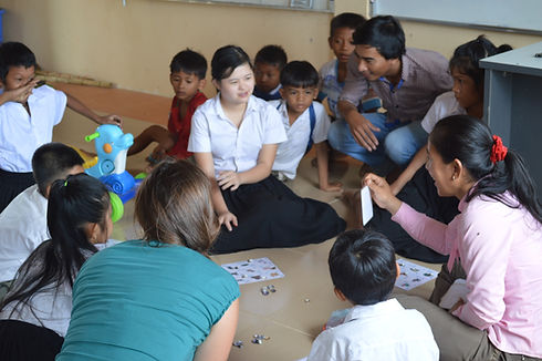 Girl with down syndrome central in focus seated on the floor surrounded by other children,
