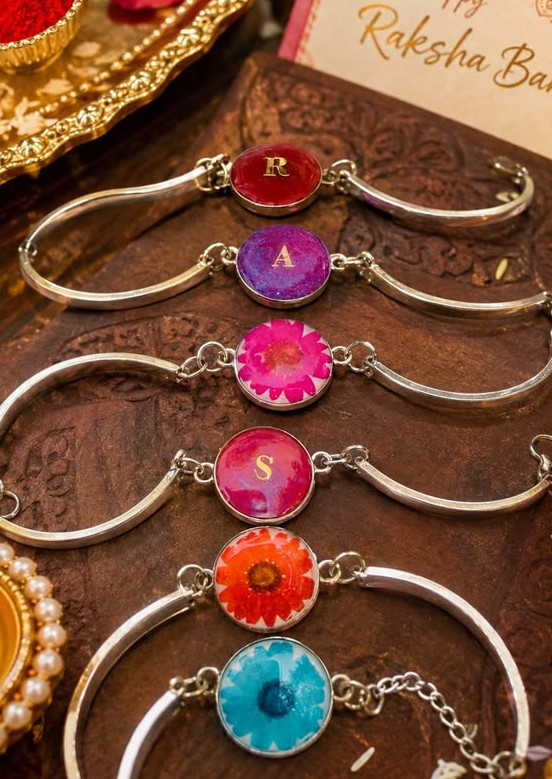 Handcrafted clear resin Rakhi featuring dried floral inclusions and gold flakes, attached to a traditional thread, showcased for Salsabila Academy's resin art workshop