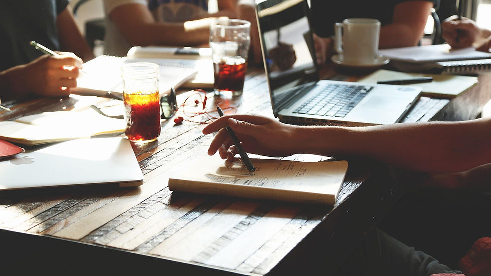 A team sitting around a table with their notebooks and laptops open