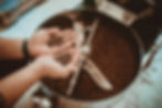 Hands holding roasted coffee beans over a coffee roaster. Warm tones create a cozy atmosphere.