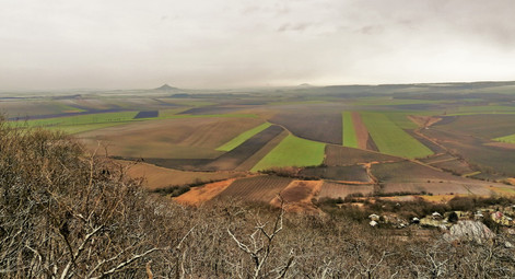 Hazmburk a Říp vystupují nad úroveň krajiny z vyhlídky na Chožovské hoře