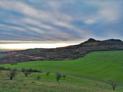 Drapérii těžkých podzimních mraků zvedá slunce nad Brníkem a Srdovem při pohledu z Křížových vršků