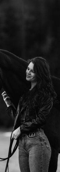 Frau steht mit ihrem Pferd auf einer Wiese und sie lächelt ihr Pferd an. Einfühlsame Pferdefotografie in Salzburg