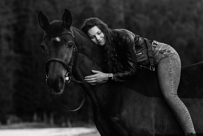 Ein schwarz-weiß Bild wo eine Frau auf ihrem Pferd liegt. Eine tiefe Verbindung ist spürbar. Pferdefotografie von Saskia Ann Fotografie