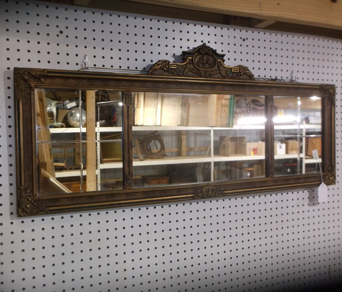 Wall mirror with three rectangular panels, framed in stepped geometric Art Deco design, reflecting light.