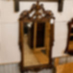 Large gold gilt wall mirror with ornate crest, urn motif, scrollwork, floral details, and carved-style frame.