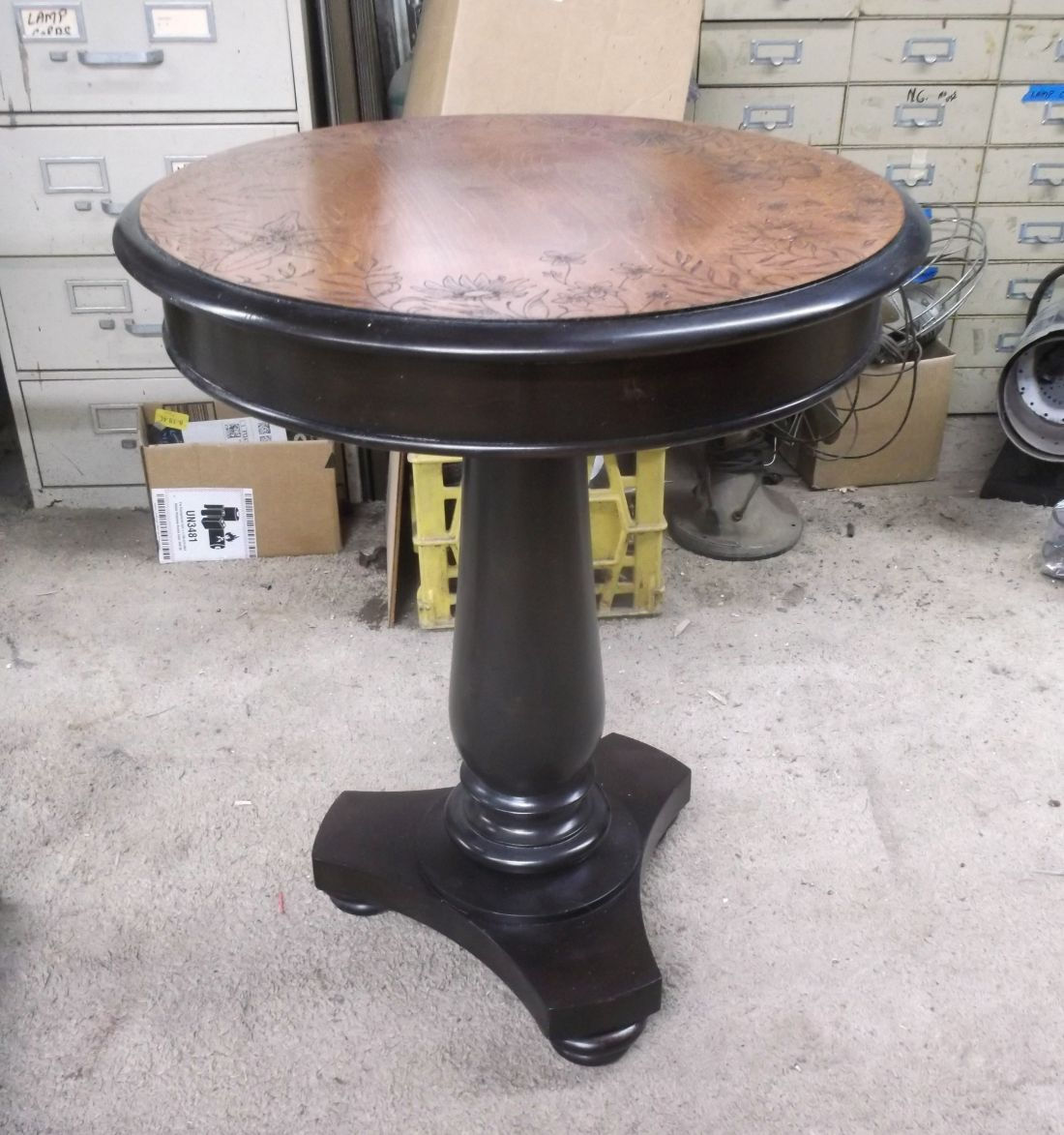 Round Empire-style side table with carved floral motifs and black painted pedestal base