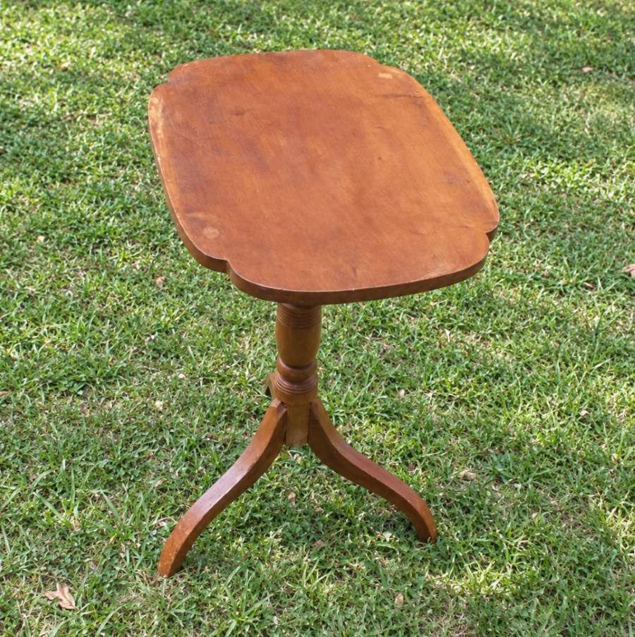Period pine tilt-top stand with a shaped rectangular top, turned center pedestal and three curved feet, photographed outdoors