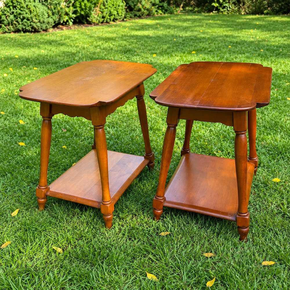 Pair of matching warm brown rock maple end tables with turned legs standing on a grass lawn.