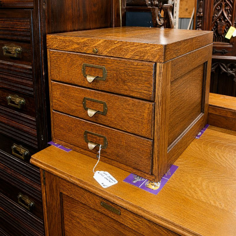 Front view of Oak three-drawer flat file with label holder pulls, paneled sides, and visible wood grain