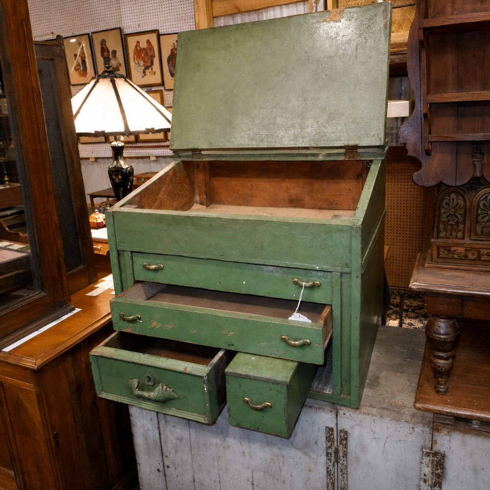 Sage-green primitive desk with its slanted lid raised and storage drawers pulled open.