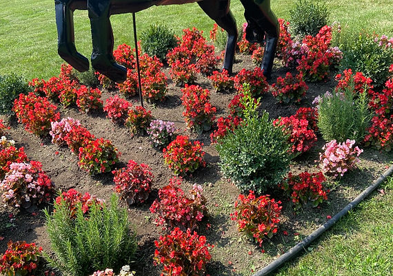 Professional landscape design featuring flower bed installation, mulch, and plants around decorative garden statue