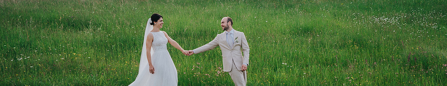 bride and groom walking in field