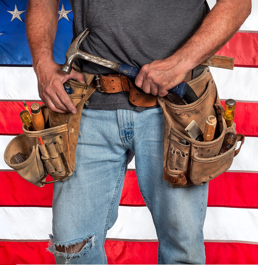 Veteran standing in front of flag wearing tool belt