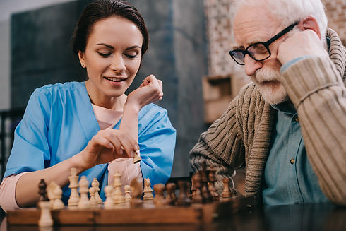Caregiver playing chess with patient