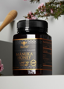 Jar of BeeNZ Manuka Honey UMF 10+ with a wooden honey dipper
