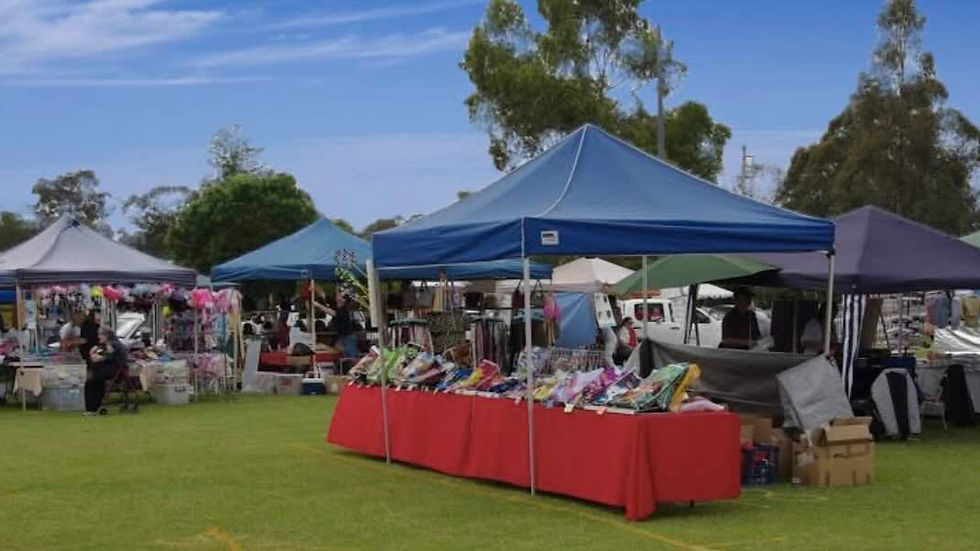3 market stalls in a field. They all have blue tops on them and are selling an array of different things.