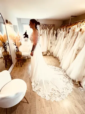 Essayage robe de mariée seconde main avec longue traîne en dentelle dans une boutique à Hazebrouck