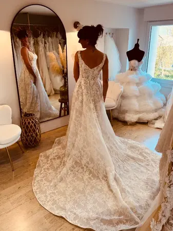 Robe de mariée seconde main en dentelle volumineuse avec traîne large essayée à Saint-Omer en boutique spécialisée