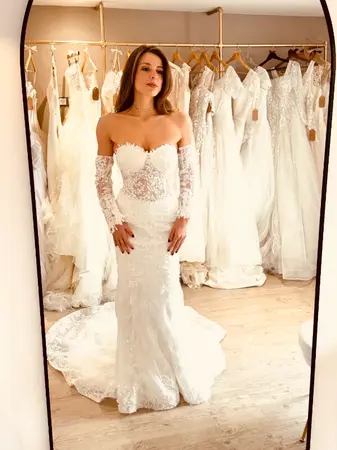 Essayage robe de mariée seconde main sirène en dentelle avec manches longues transparentes à Béthune en boutique spécialisée