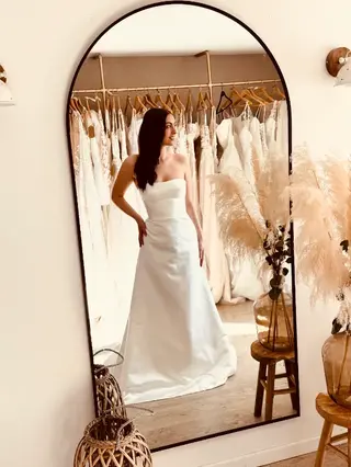 Future mariée portant une robe de mariée seconde main sirène bustier en satin style minimaliste en boutique spécialisée