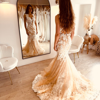 Robe de mariée sirène en dentelle avec bas légèrement coloré et traîne sophistiquée, essayée en boutique près de Saint-Omer