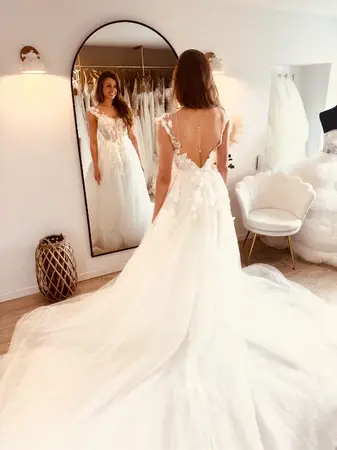 Essayage robe de mariée seconde main fluide avec longue traîne élégante à Béthune en boutique