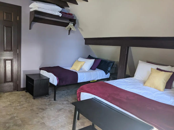 The master bedroom accommodates a king bed which has a mauve blanket.