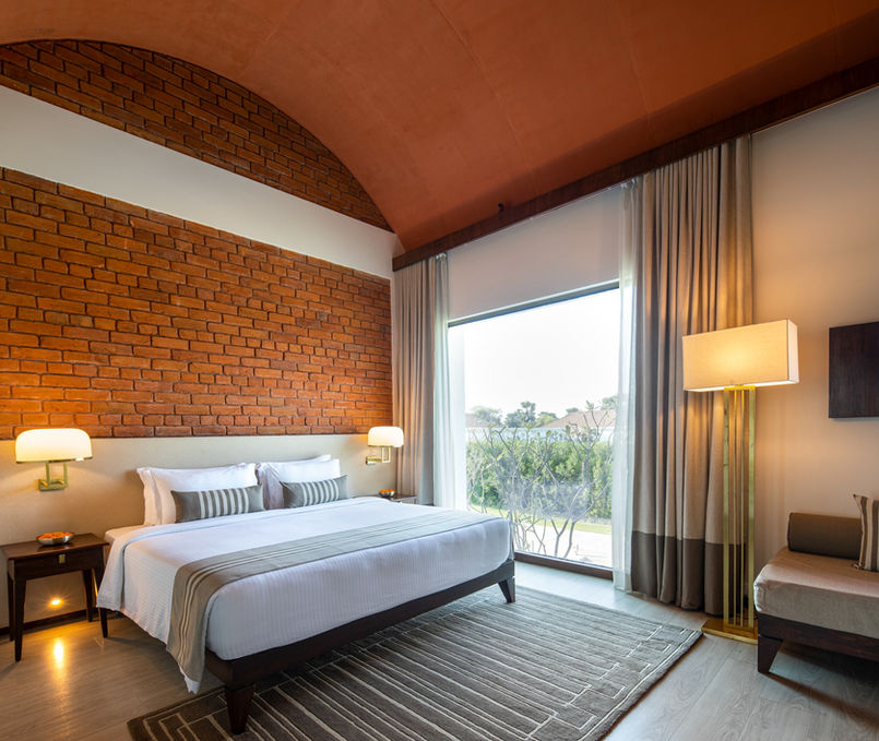 Vaulted ceiling in a hotel room, terracotta ceiling, brick wall cladding, geometric rug design in a hotel room, terracotta and white hotel room, warm colour palette of a hotel room, wooden flooring in a hotel room, Buddhism inspired hotel interior design