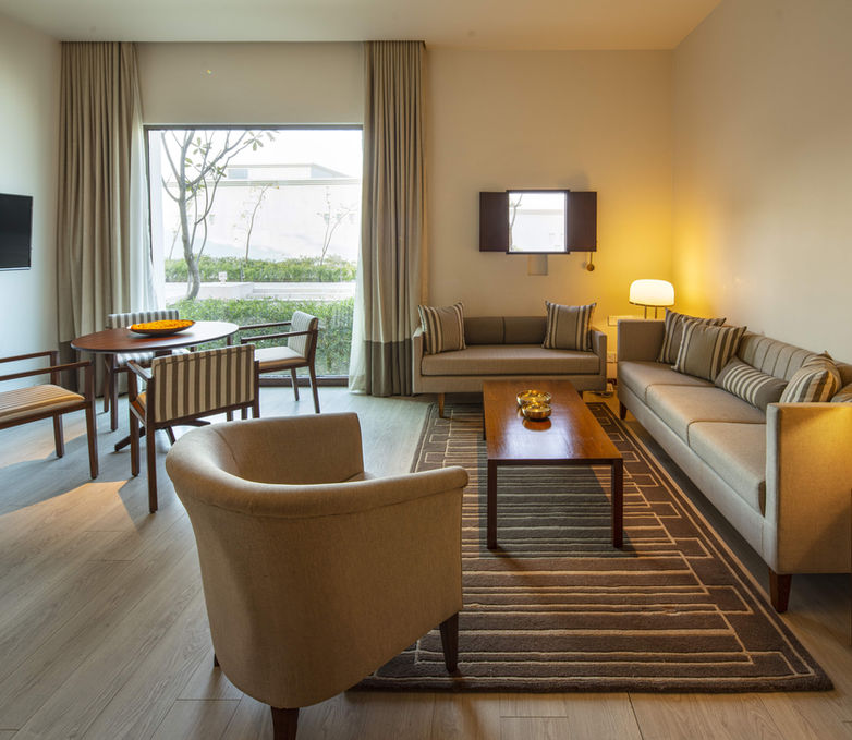 Hotel suite room design, geometric rug design, small window in a hotel room, dining area in a suite room, living area in a suite room, wooden flooring in a hotel room, contemporary hotel design, Buddhism inspired hotel interior design