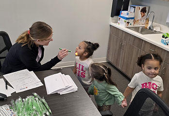Dental hygienist completing a dental screening on young child at a preschool.