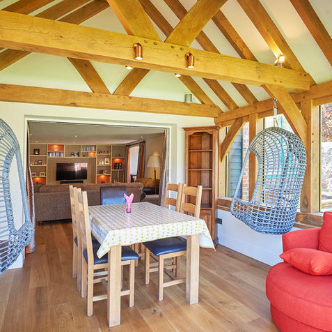 A stylish living room with a dining table and chairs, part of an oak garden room extension by Hartwood Oak in Berkshire.