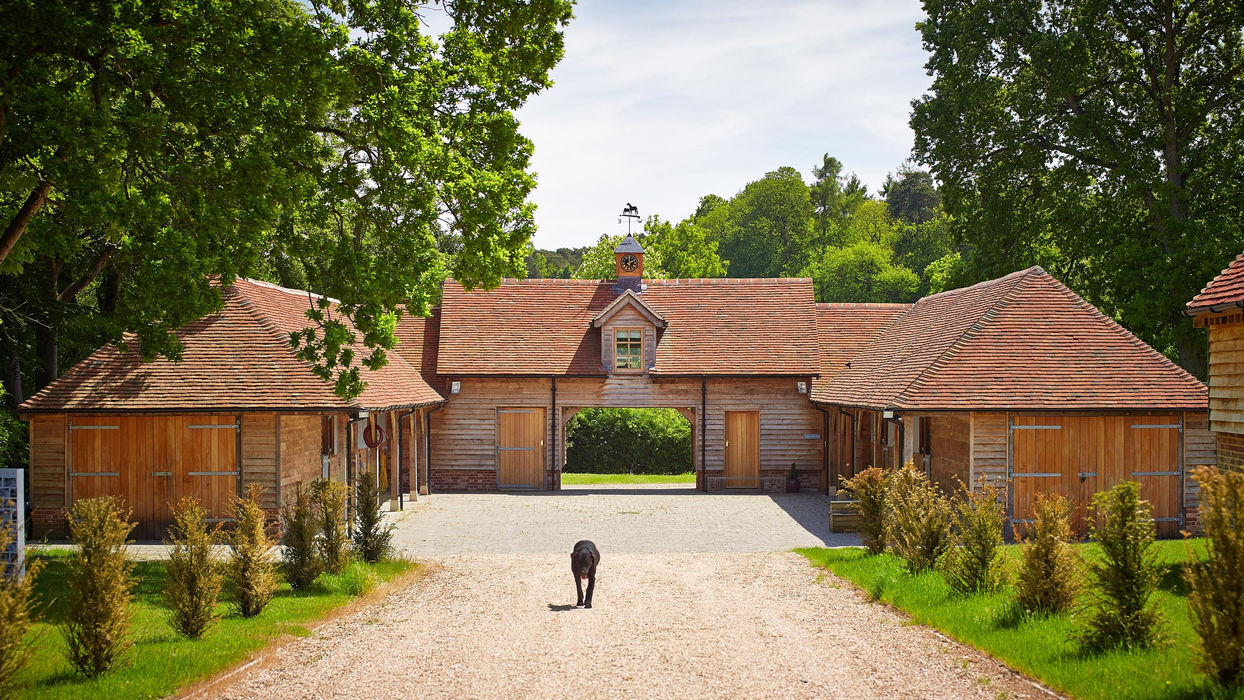 The Oak Stables pool house features a barn with a clock on the roof, located in Ascot by Hartwood Oak.