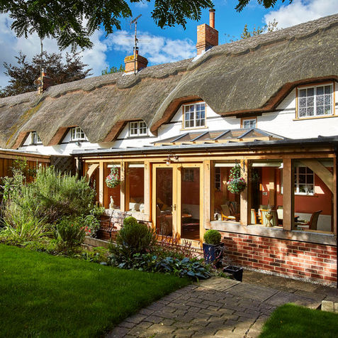 A picturesque thatched house with a garden and patio, including an oak orangery in Ashampstead by Hartwood Oak.