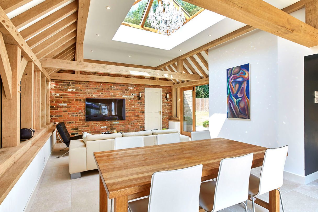 A cozy living room featuring a skylight and wooden beams, showcasing the oak orangery design by Hartwood Oak in Burghclere.
