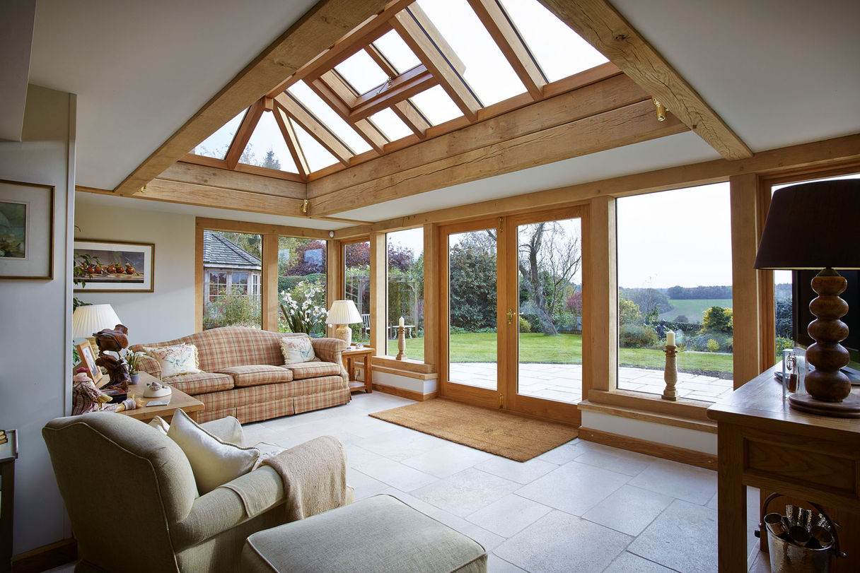Spacious Oak Orangery in Ashampstead by Hartwood Oak, featuring a large glass door and a TV for entertainment.
