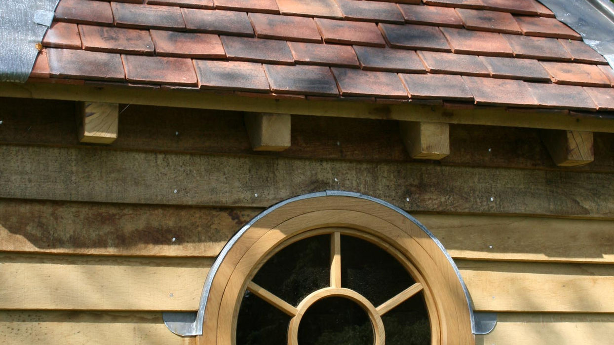 Oak hen house by Hartwood Oak, featuring a wooden structure with a roof and door, set in a garden.