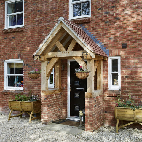 A cozy brick house with a wooden door and an oak porch designed by Hartwood Oak, located in Berkshire.