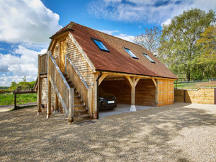 Oak-framed garage with timber cladding, external staircase and three open parking bays.