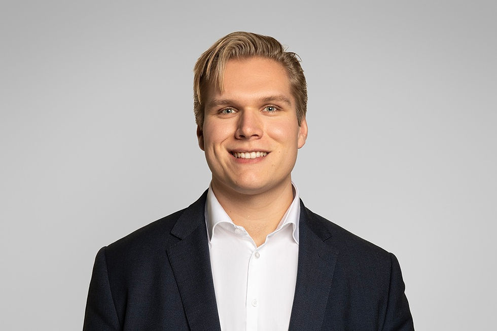 Portretfoto van Kars Nicolai in pak op grijze achtergrond