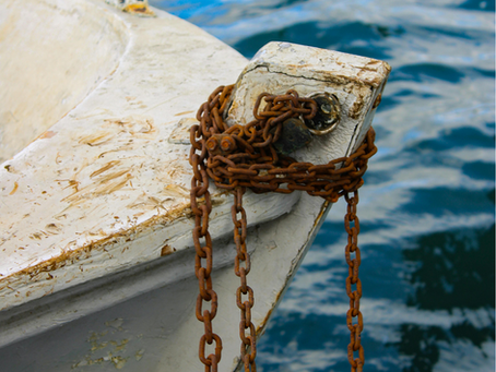 Rusty chain on a weathered boat's prow, set against a rippling blue water background, evokes a sense of nautical nostalgia.
