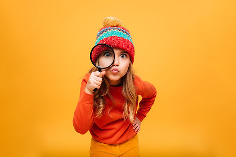 joyeuse-jeune-fille-pull-chapeau-regardant-camera-loupe-orange.jpg