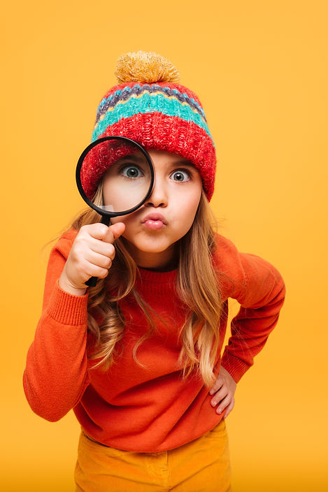 joyeuse-jeune-fille-pull-chapeau-regardant-camera-loupe-orange.jpg