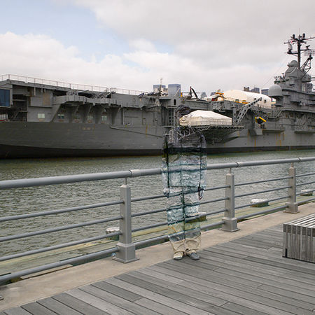 Aircraft carrier docked with a ghosted image of a person in the foreground.