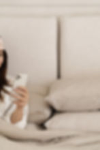 Cozy Woman reviewing her Spellbound Leisure Itinerary on her mobile phone from the comfort of her own bed